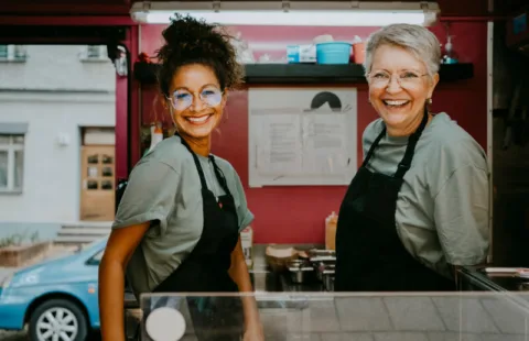 Two women in aprons working together at food truck window