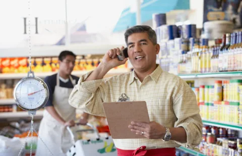 Man talking on phone while holding clipboard in grocery store